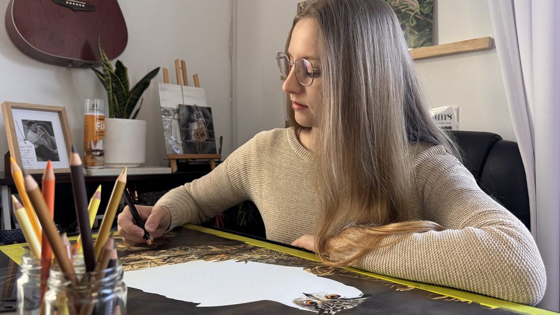 Nicci Sims drawing a coloured pencil owl portrait at her desk